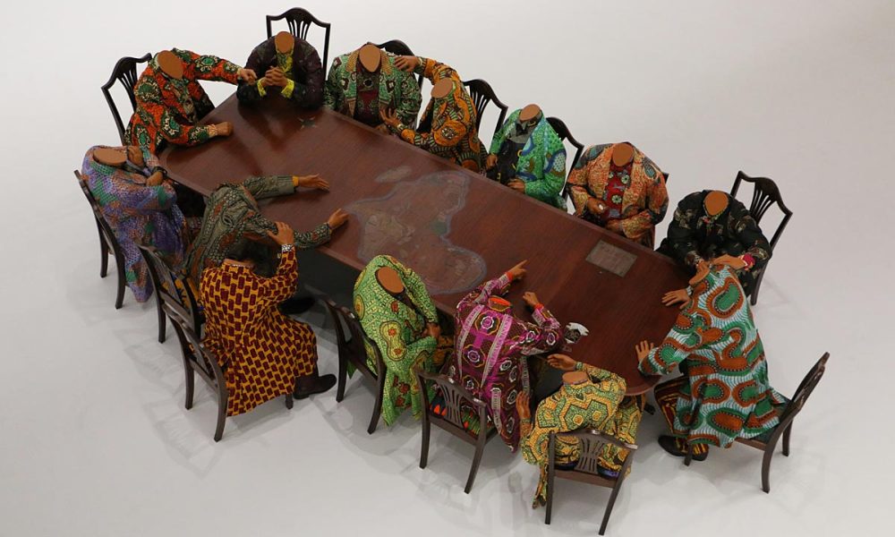 Shonibare, Yinka, The scramble for Africa (La lucha por África), 2003.14 maniquíes de fibra de vidrio de tamaño real, 14 sillas, 1 mesa, algodón estampado de cera holandesa. ©The Pinnell Collection, Dallas